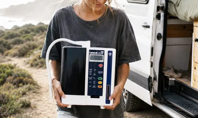 Um viajante segurando o compacto LeveLuk JR IV ao lado de uma autocaravana na costa