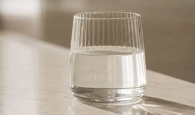 Um copo canelado de Kangen Water® clara num balcão iluminado pelo sol